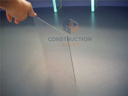 A hand holding a frosted polycarbonate sheet upright, showing both the frosted and glossy sides with Constructionmart branding.