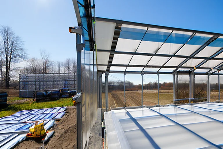 Close-up of a person safely brushing snow off a multiwall polycarbonate greenhouse roof in winter.